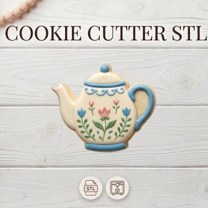 Peut inclure: Emporte-pièce en forme de théière avec des motifs floraux bleus et roses. Le découpoir à biscuits a une anse et une bordure bleues. Le texte "COOKIE CUTTER STL" est en haut de l'image.