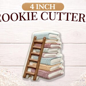May include: A 4-inch cookie cutter in the shape of a stack of books with a wooden ladder. The books are in shades of blue, pink, and tan. The text "4 INCH COOKIE CUTTERS" is at the top.