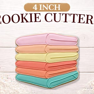 May include: A stack of colorful cookie cutters in the shape of books. The cutters are 4 inches in size and are in shades of pink, orange, yellow, coral, and teal. The words "4 INCH COOKIE CUTTERS" are printed above the cutters.