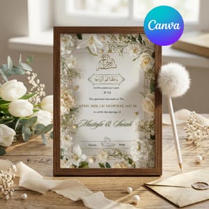 May include: A vertical wooden frame containing a marriage certificate with white floral borders. The text includes the names Mustafa & Sarah, the date April 2026, and Arabic calligraphy. A white fluffy pen and an envelope are placed nearby.