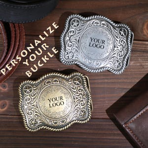 May include: Two decorative metal belt buckles, one silver and one bronze, with space for a logo. The buckles have a star and scroll design. The image includes the text "PERSONALIZE YOUR BUCKLE".