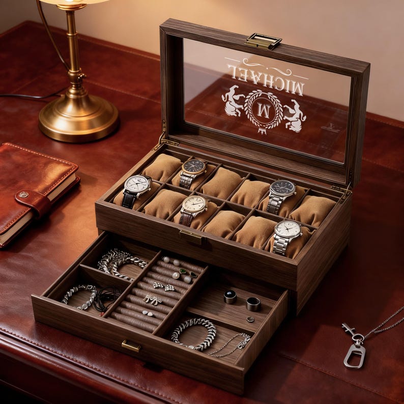 May include: A wooden watch and jewelry box with a glass top, displaying several watches on brown cushions. The box has a drawer with compartments for jewelry. The glass top is etched with the name "MICHAEL" and a crest.