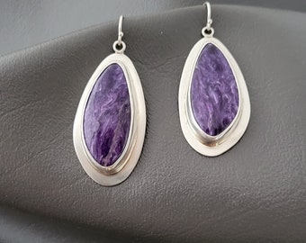 May include: A pair of silver dangle earrings with purple, swirled, gemstone drops.