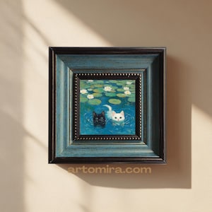 Puede incluir: Obra de arte enmarcada cuadrada que presenta una pintura de dos gatos nadando en un estanque con nenúfares y flores blancas. Un gato es negro, el otro blanco. El marco es azul con un borde interior marrón oscuro. El sitio web artomira.com está impreso en la parte inferior.