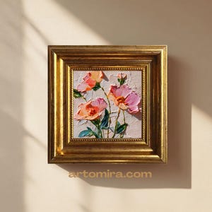 Könnte beinhalten: Quadratisches, gerahmtes Ölgemälde mit rosa und orangefarbenen Blumen und grünen Blättern. Das Kunstwerk ist vor einem strukturierten, weißen Hintergrund in einem goldfarbenen, verzierten Rahmen eingefasst. Die Website artomira.com ist unten sichtbar.