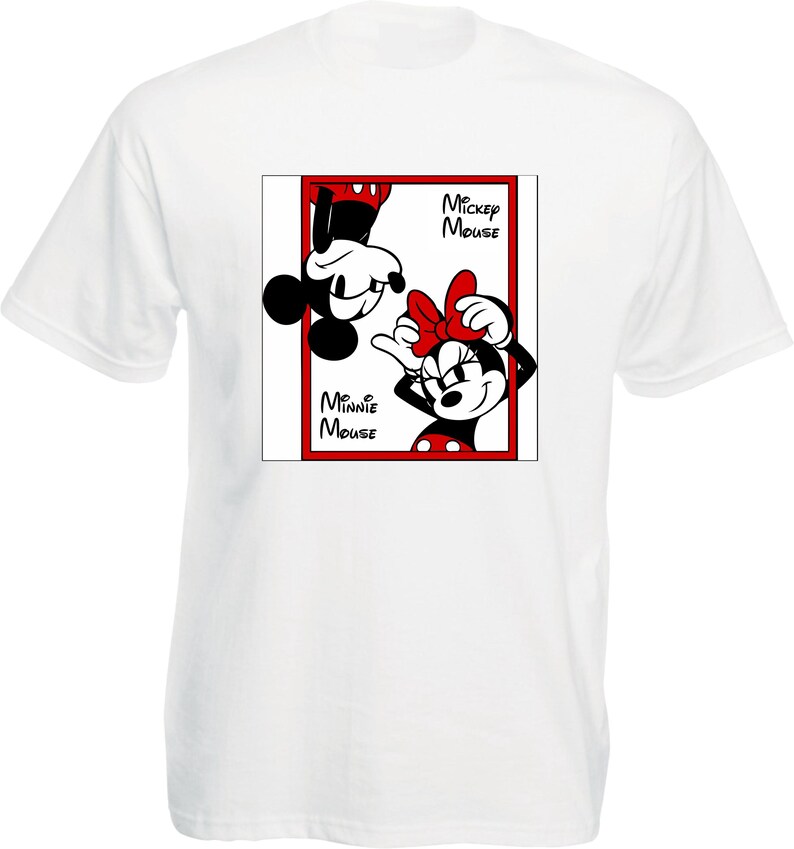 May include: White t-shirt featuring a graphic of Mickey and Minnie Mouse in a red-bordered frame. Mickey is upside down, and Minnie is upright, both smiling. The words "Mickey Mouse" and "Minnie Mouse" are printed on the frame.