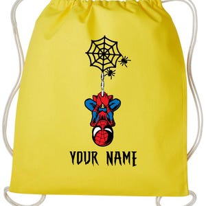 Puede incluir: Mochila con cord&oacute;n amarilla con un dise&ntilde;o de Spider-Man. El dise&ntilde;o incluye una telara&ntilde;a, ara&ntilde;as y el texto "YOUR NAME" en negro. La mochila tiene cordones blancos.