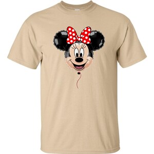 Pu&ograve; includere: T-shirt color cachi con un design a palloncino di Minnie Mouse. Il palloncino ha orecchie nere, una faccia sorridente e un fiocco rosso a pois bianchi. Un filo rosso pende sotto.