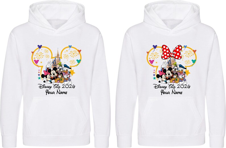 May include: Two white hooded sweatshirts featuring a graphic of Mickey Mouse, Minnie Mouse, Goofy, Donald Duck, and Pluto in front of a castle. The design includes a yellow Mickey-shaped outline, fireworks, and the text Disney Trip 2026 Your Name.