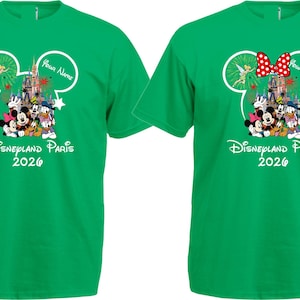May include: Two green t-shirts with a Disney theme. Each shirt features a Mickey Mouse head outline with a castle, characters, and the text "Disneyland Paris 2026." One shirt has a red polka dot bow.