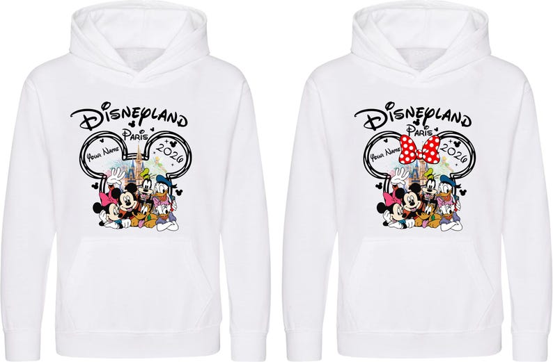 Puede incluir: Sudaderas con capucha blancas con un dise&ntilde;o de Disneyland Par&iacute;s. El gr&aacute;fico incluye a Mickey Mouse, Minnie Mouse, el Pato Donald, Goofy y Pluto. El dise&ntilde;o presenta el texto "Disneyland Par&iacute;s 2020" y un espacio para un nombre. Una sudadera tiene un lazo rojo de lunares.