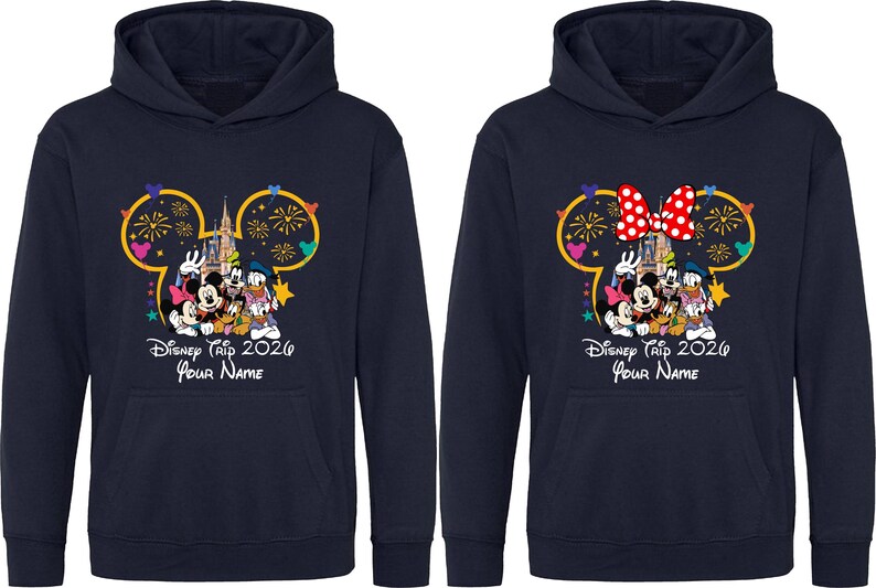 May include: Two navy blue hooded sweatshirts featuring a graphic of Disney characters in front of a castle with fireworks inside a Mickey Mouse silhouette outline. The text reads Disney Trip 2026 and Your Name, with one hoodie featuring a red polka dot bow.