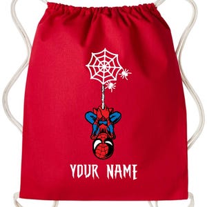Puede incluir: Mochila roja con cord&oacute;n con un dise&ntilde;o de Spider-Man. Presenta una telara&ntilde;a blanca, ara&ntilde;as y una ilustraci&oacute;n de Spider-Man boca abajo. El texto "YOUR NAME" est&aacute; impreso en blanco en la parte inferior. Cordones blancos.