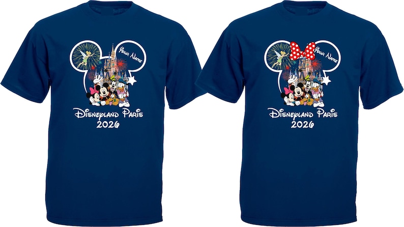 May include: Two navy blue t-shirts featuring a Disney design. The design includes Mickey Mouse ears, a castle, and various Disney characters. The text "Disneyland Paris 2026" is printed below the characters. One shirt has a red bow.