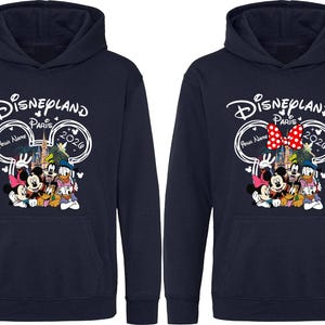 Puede incluir: Sudaderas con capucha azul marino con un dise&ntilde;o de Disneyland Paris 2020. El dise&ntilde;o incluye a Mickey Mouse, Minnie Mouse, Donald Duck y Goofy. Una sudadera tiene un lazo rojo, la otra no.