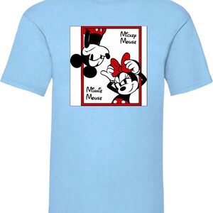 May include: Light blue t-shirt featuring a graphic of Mickey and Minnie Mouse. The design includes Mickey Mouse upside down and Minnie Mouse with a red bow. The words "Mickey Mouse" and "Minnie Mouse" are also in the design.