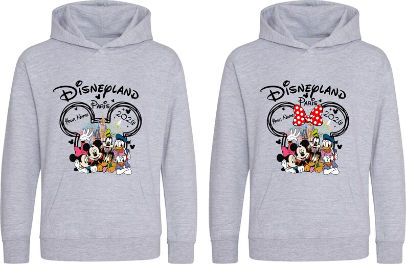 Puede incluir: Dos sudaderas con capucha de color gris claro con un gr&aacute;fico de Disneyland Paris 2020 con Mickey Mouse, Minnie Mouse, Donald Duck y Goofy. Una sudadera con capucha tiene un lazo rojo y blanco. La otra tiene un lazo negro.