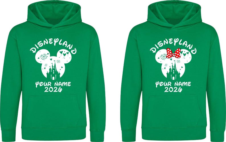 May include: Two green Disneyland hoodies. One features a white Mickey Mouse head with a castle silhouette, fireworks, and the text "YOUR NAME 2026". The other has a red bow.