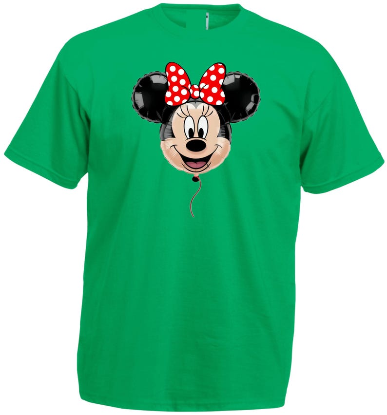 Pu&ograve; includere: Una maglietta verde con un disegno a palloncino di Minnie Mouse. Il palloncino ha orecchie nere, una faccia sorridente e un fiocco rosso a pois bianchi. Un filo rosso pende dal fondo del palloncino.
