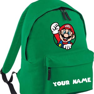 May include: Green backpack with a cartoon image of Mario in a black circle. The backpack has a front pocket with the text "YOUR NAME" in white. The bag has black zippers and straps.