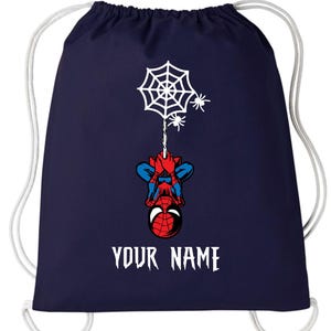 Puede incluir: Mochila con cord&oacute;n de color azul marino con un dise&ntilde;o de Spider-Man. El dise&ntilde;o incluye una telara&ntilde;a blanca, dos peque&ntilde;as ara&ntilde;as y el texto "YOUR NAME" en blanco. El superh&eacute;roe est&aacute; colgado boca abajo. Cierre con cord&oacute;n blanco.
