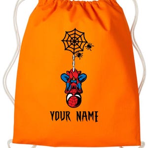 Puede incluir: Mochila con cord&oacute;n naranja con un dise&ntilde;o de Spider-Man. El superh&eacute;roe est&aacute; colgado de una telara&ntilde;a. El texto "YOUR NAME" est&aacute; impreso en negro debajo. Cordones blancos.