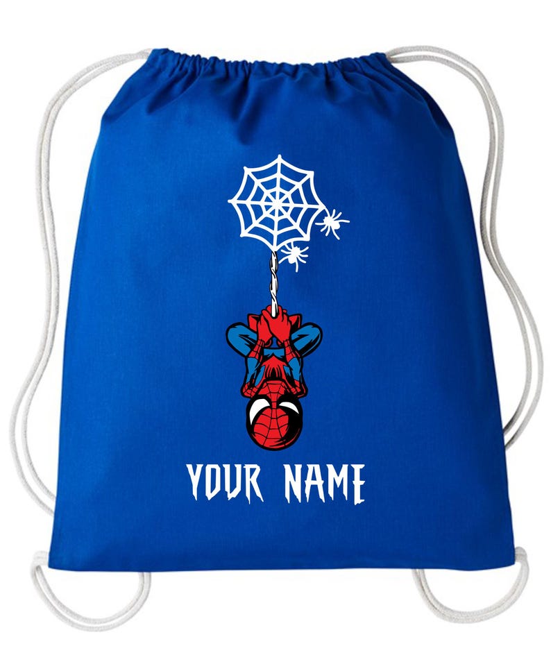 Puede incluir: Mochila con cord&oacute;n azul con un dise&ntilde;o de Spider-Man colgando de una telara&ntilde;a con dos ara&ntilde;as. La mochila tiene cordones blancos y el texto "YOUR NAME" en blanco.