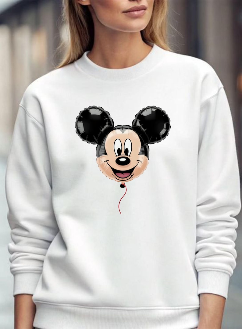 May include: White sweatshirt featuring a Mickey Mouse balloon design. The balloon has black ears, a smiling face, and a red string. The sweatshirt is a solid white color.