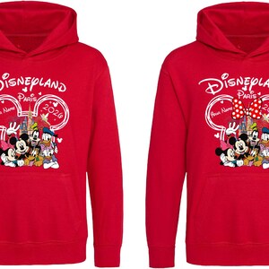 Puede incluir: Dos sudaderas rojas con capucha con un dise&ntilde;o de Disneyland Paris 2026. El dise&ntilde;o presenta a Mickey Mouse, Minnie Mouse, Donald Duck y Goofy. Las sudaderas tienen un bolsillo delantero y una capucha.
