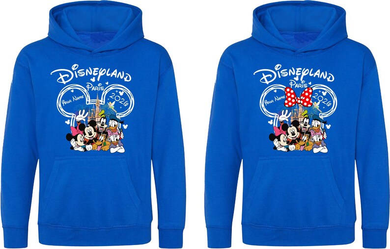 Puede incluir: Dos sudaderas azules con un gr&aacute;fico de Disneyland Paris 2020. El gr&aacute;fico presenta a Mickey y Minnie Mouse, el Pato Donald y Goofy. Una sudadera tiene un lazo rojo y blanco. La otra tiene un espacio en blanco para un nombre.