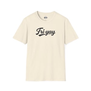 Puede incluir: Camiseta color crema con la palabra "Fri-yay" en escritura negra en la parte delantera. La camiseta tiene cuello redondo y mangas cortas. La tela tiene una textura moteada.