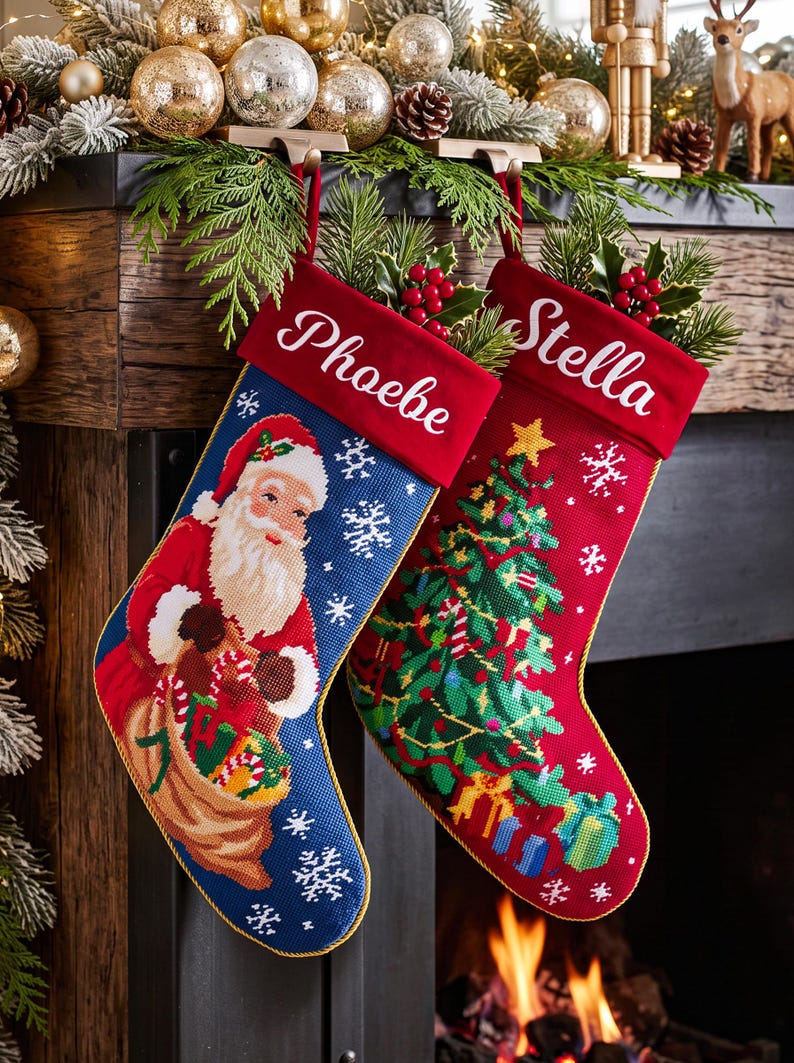 May include: Two needlepoint Christmas stockings with red velvet cuffs. The blue stocking features Santa Claus with a gift sack, while the red stocking displays a decorated Christmas tree. The names Phoebe and Stella are embroidered in white script.