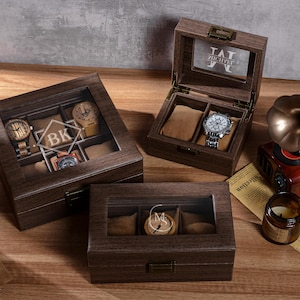 Pode incluir: Caixas de exibição de relógios de madeira com tampas de vidro, exibindo vários relógios. Uma caixa está aberta, revelando um relógio com uma pulseira prateada. Um gramofone de estilo vintage e uma vela acesa também estão presentes.