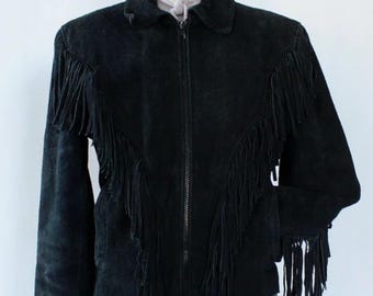 Puede incluir: Chaqueta de ante negra con flecos. La chaqueta tiene cuello, cierre de cremallera frontal y mangas largas. Los flecos están en la parte delantera y en las mangas. La chaqueta se exhibe en un maniquí.