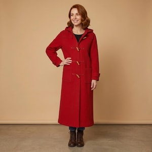 May include: A long, bright red wool-blend duffle coat featuring a hood, a high neckline, and three wooden toggle closures down the front. The coat includes two large patch pockets on the front and long sleeves with cuffs, extending to the mid-calf.