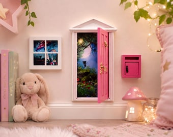 May include: A miniature pink fairy door with a gold handle and knocker, featuring a white frame and a view of a magical forest scene. Beside it is a small matching pink mailbox, a square window with a forest print, and a plush beige bunny toy.