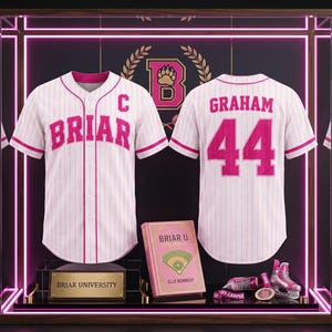 Könnte beinhalten: Ein weißes Baseballtrikot mit rosa Nadelstreifen, dem Wort BRIAR und einem C auf der Vorderseite sowie GRAHAM 44 auf der Rückseite. Ein Buch mit dem Titel BRIAR U: SERIES MEMORIAL, eine Medaille und ein rosa-weißer Schlittschuh in einer Vitrine.