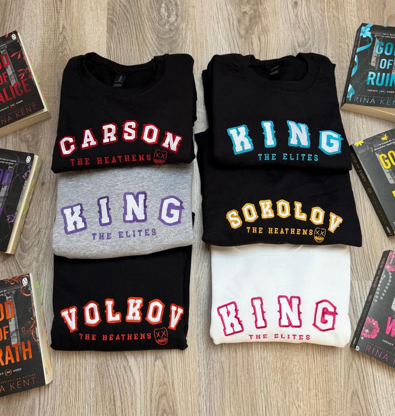 K&ouml;nnte beinhalten: Eine Sammlung von Sweatshirts in Schwarz, Grau und Wei&szlig;, jedes mit fettem Text. Die Sweatshirts zeigen Namen wie "CARSON", "KING", "SOKOLOV" und "VOLKOV" sowie S&auml;tze wie "THE HEATHENS" und "THE ELITES".