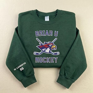 May include: A dark green sweatshirt with the text "BRIAR U HOCKEY" and a logo of a stylized eagle with crossed hockey sticks. The sleeve has the text "DI LAURENTIS 66".
