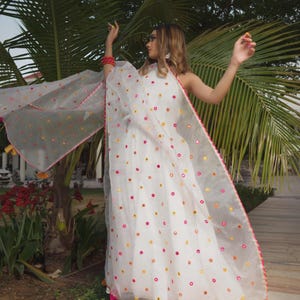 A white dress and matching sheer shawl, both adorned with colorful circular embellishments. The shawl is trimmed with pink and orange accents.