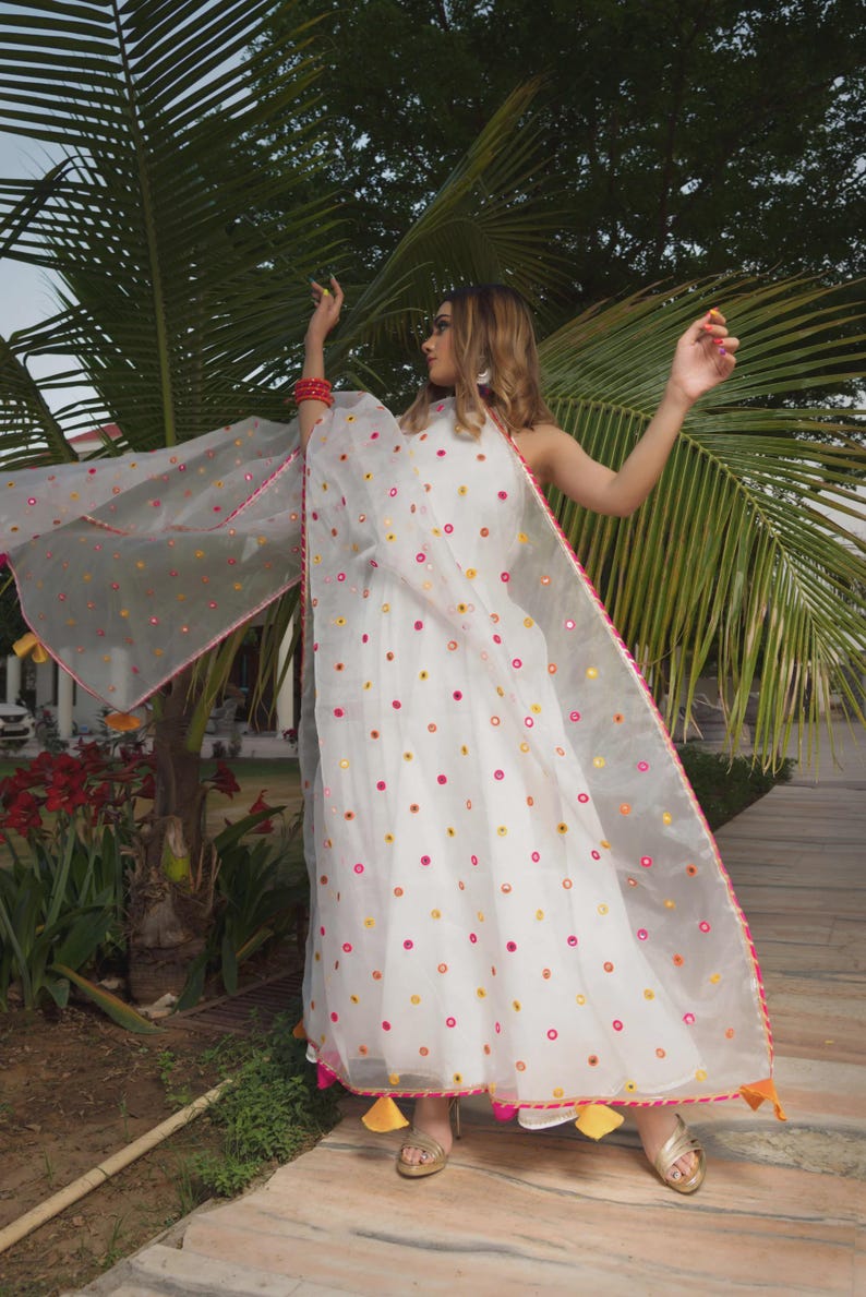 A white dress and matching sheer shawl, both adorned with colorful circular embellishments. The shawl is trimmed with pink and orange accents.