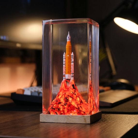 An Artemis II astronaut figure mid-mission cast inside a glowing epoxy resin lamp — 26 favorites confirms people see it as genuine space-nerd art, not just another lamp.