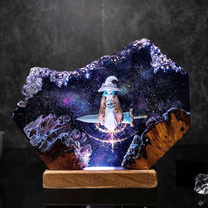 Pode incluir: Escultura decorativa em resina com uma figura de mago com uma espada, contra um fundo de gal&aacute;xia estrelada. A escultura &eacute; montada numa base de madeira, com ilumina&ccedil;&atilde;o interna que ilumina a cena da gal&aacute;xia. O mago usa um chap&eacute;u e uma capa.
