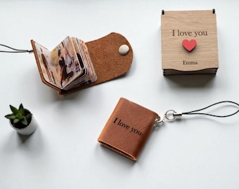 May include: A collection of personalized gifts, including a small leather photo album, a wooden box with "I love you" and a red heart, and a miniature leather book with "I love you" printed on it. A small potted plant is also present.