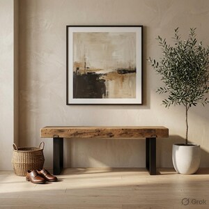 May include: A rectangular wooden bench with a thick, textured top and black metal legs. Above the bench hangs a square framed abstract painting featuring shades of beige, cream, and dark brown. To the left sits a woven basket and brown leather shoes.