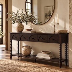 Puede incluir: Una mesa consola de madera de color marrón oscuro con cinco cajones que presentan detalles arqueados y pequeños pomos negros. La mesa se apoya sobre cuatro patas de estilo huso e incluye un estante inferior para almacenamiento y objetos decorativos.