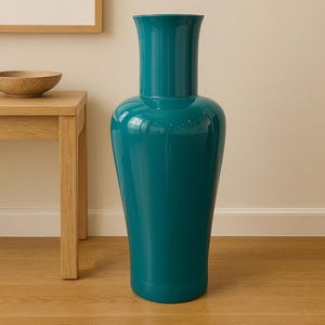 Puede incluir: Un jarrón alto de cerámica de color turquesa con un acabado brillante. El jarrón tiene un cuerpo ancho y redondeado que se estrecha hacia una base estrecha y una parte superior acampanada. Se encuentra sobre un suelo de madera, con una mesa de madera y una obra de arte en el fondo.