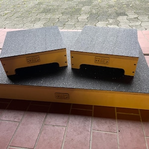 May include: Three wooden plyometric boxes with a textured, dark grey surface. The boxes are yellow on the sides and have a rectangular shape. Two smaller boxes sit on top of a larger one.