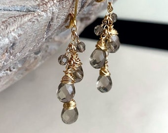 May include: A pair of gold-toned dangle earrings with multiple smoky quartz teardrop-shaped beads. The earrings are made with wire wrapped beads and have a simple hook closure.