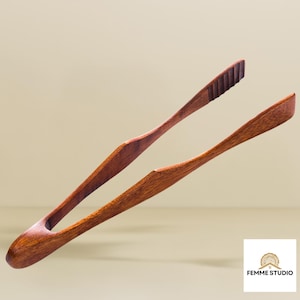 Puede incluir: Pinzas de servir de madera con acabado natural. Las pinzas son de madera marrón oscuro y tienen un diseño ranurado para facilitar el manejo. Las puntas de las pinzas están anguladas para agarrar. Ideales para servir ensaladas, pasta u otros platos. Longitud aproximada 25 cm.